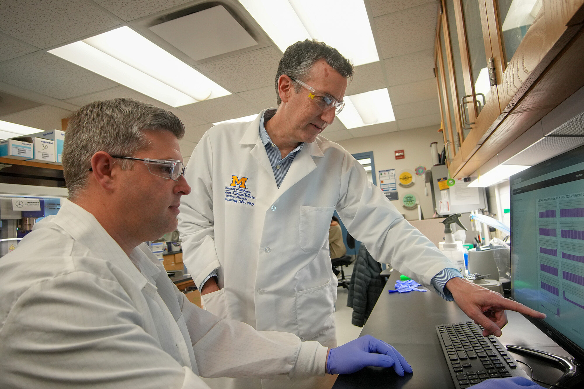 Image of Dr. Lauring and research lab specialist Will Fitzsimmons working on a computer in a lab setting